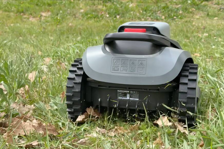 TerraMow V1000 Mähroboter fährt einen Hang herunter und mäht eine Bahn im hohen Gras im Test